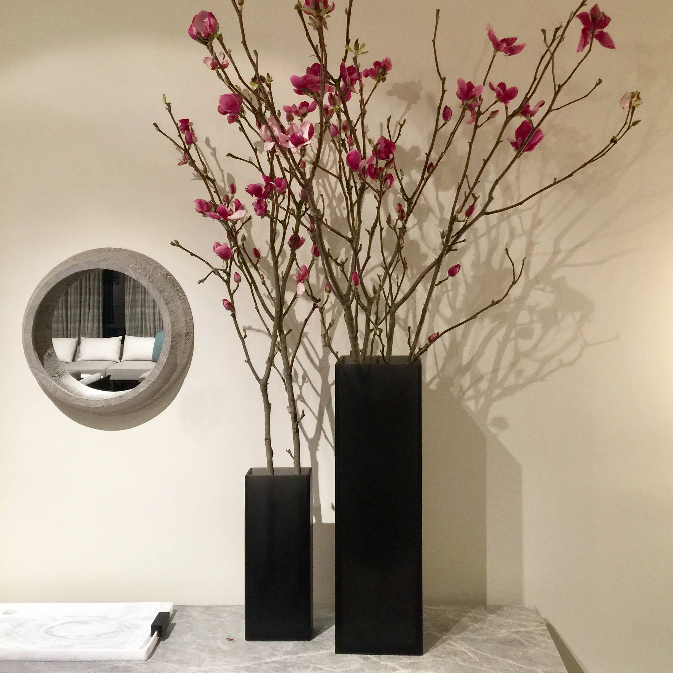 Flowering quince branches in tall black vessels