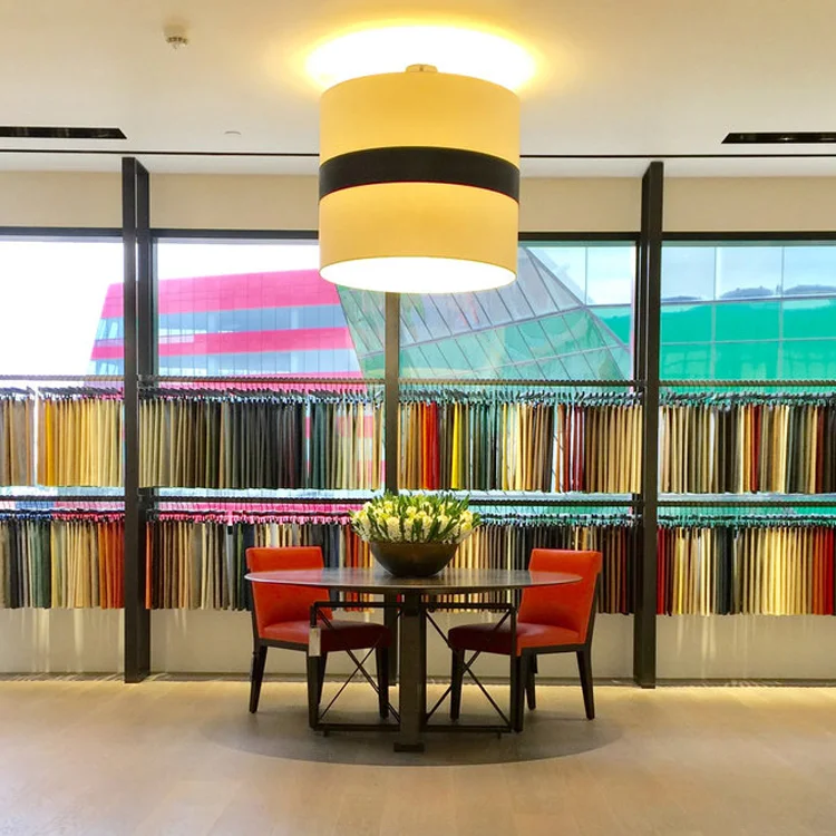 A leaf-lined bowl of ivory blooms grounds a reading table ringed in red chairs.
