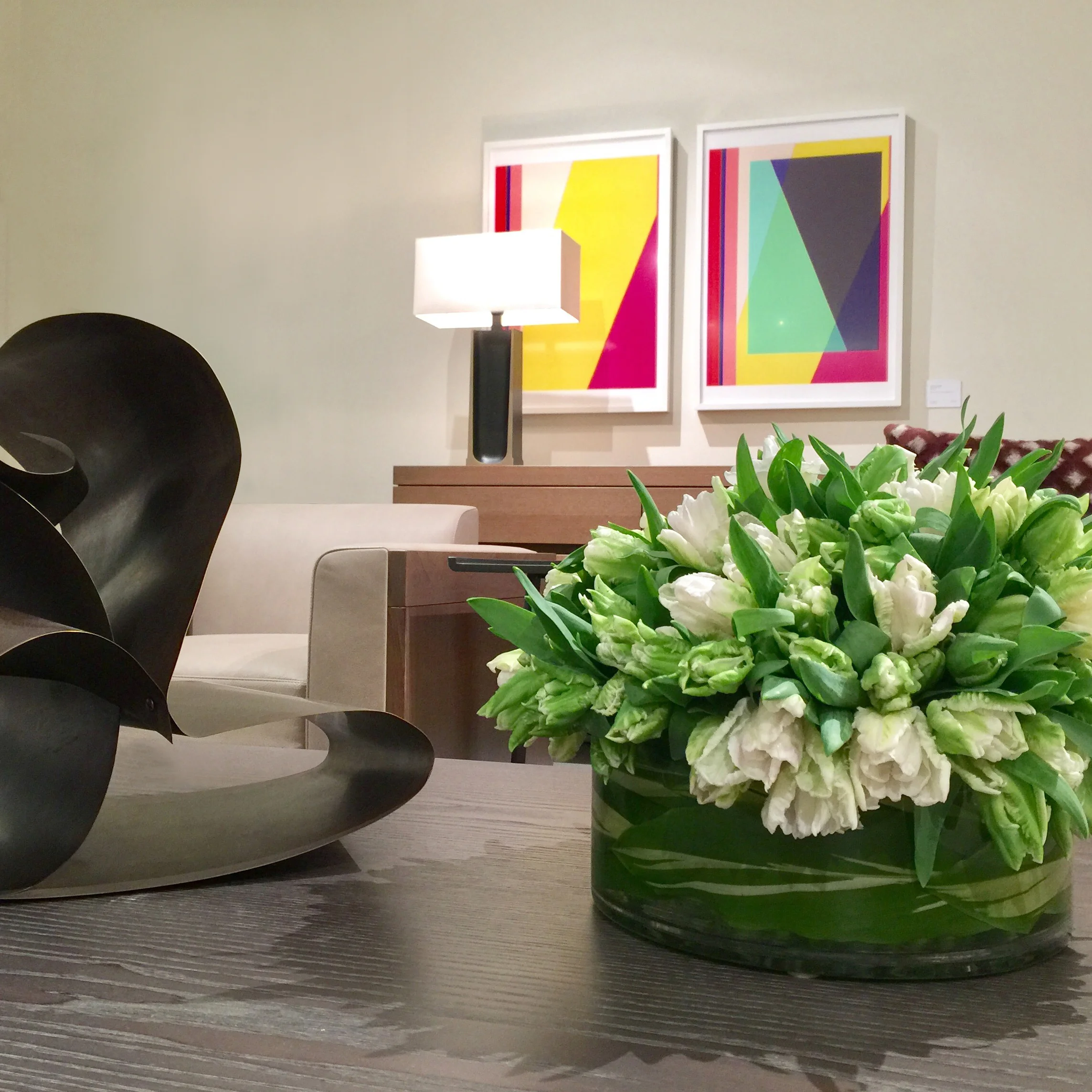 Parrot tulips in leaf-lined glass beneath contemporary art